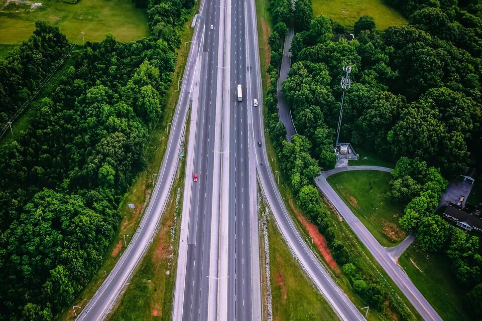Aerial view of an interstate highway cutting through green forest