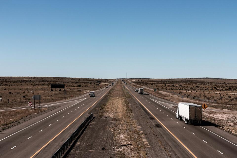 Semi truck on a wide open desert interstate under a clear sky
