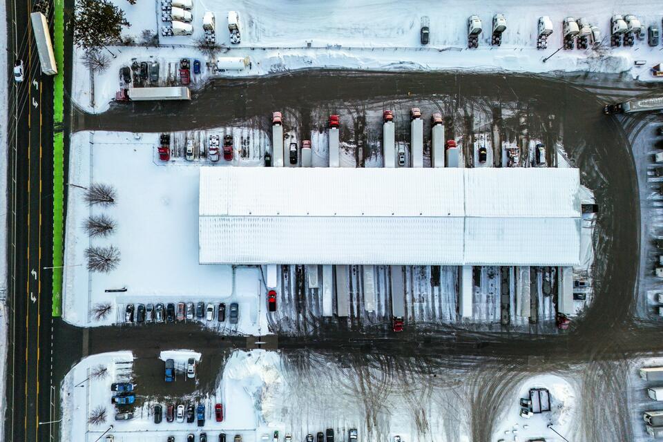 Aerial view of trailers lined up at the dock doors of a snowy distribution center