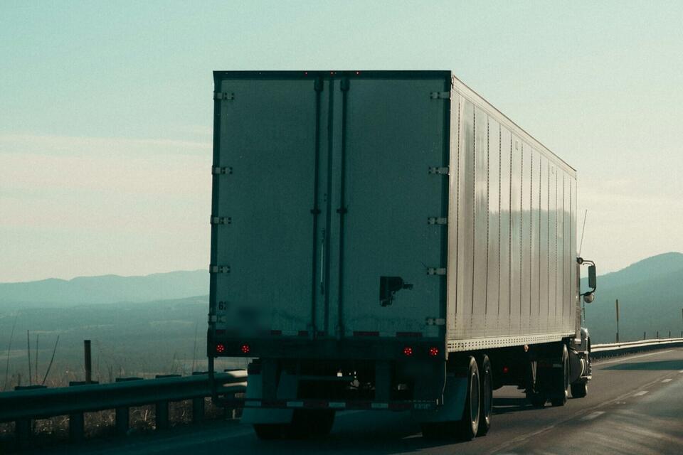 Trailer on a highway heading toward distant hills