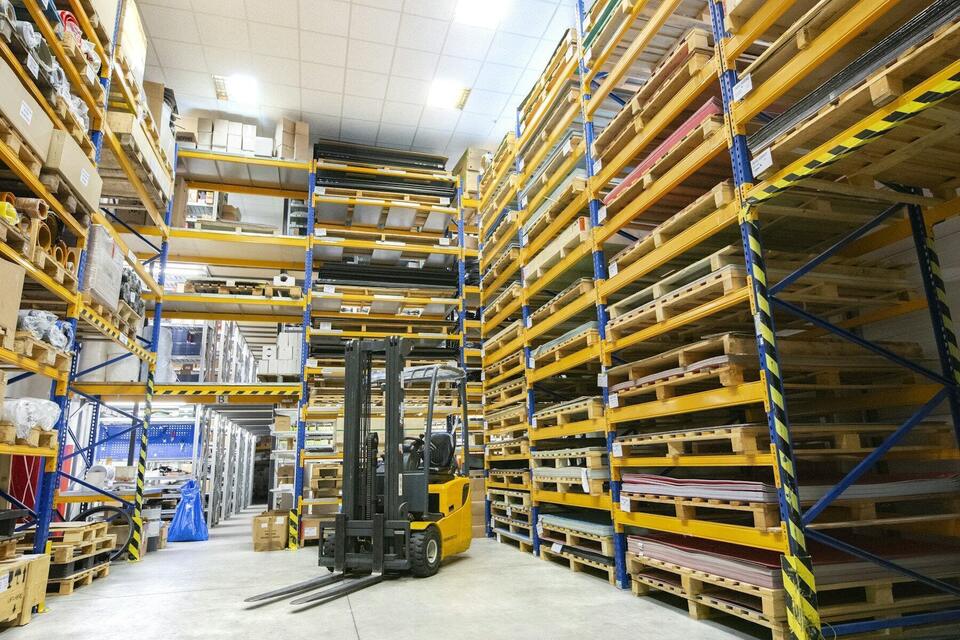 Tall warehouse racking with pallets and a forklift in the aisle